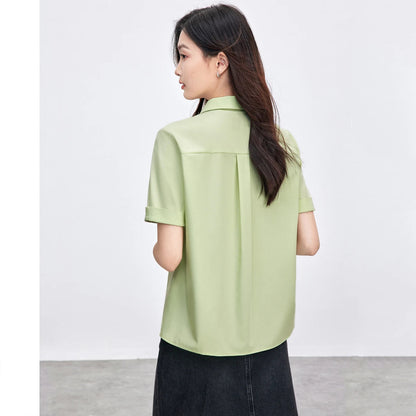 Woman wearing a light green shirt with a plain background.