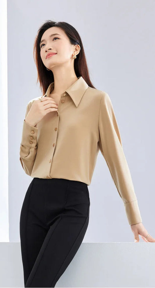 Woman wearing a beige blouse and black pants against a white background